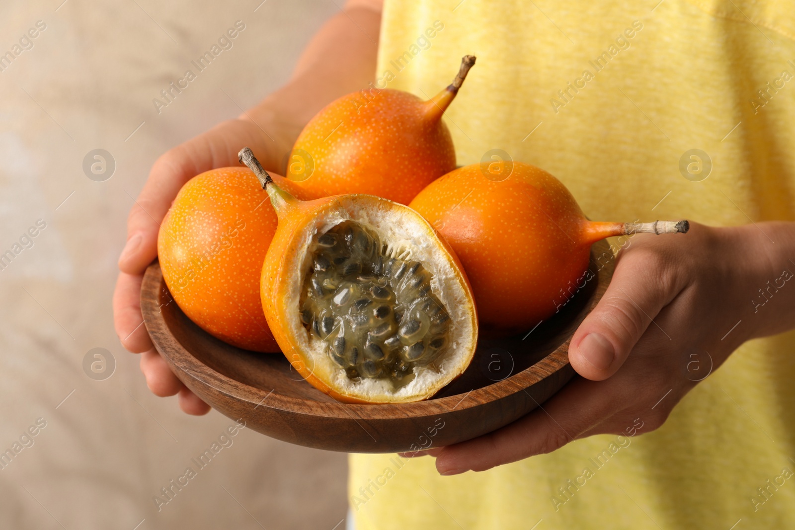 Photo of Woman with ripe granadillas on beige background, closeup