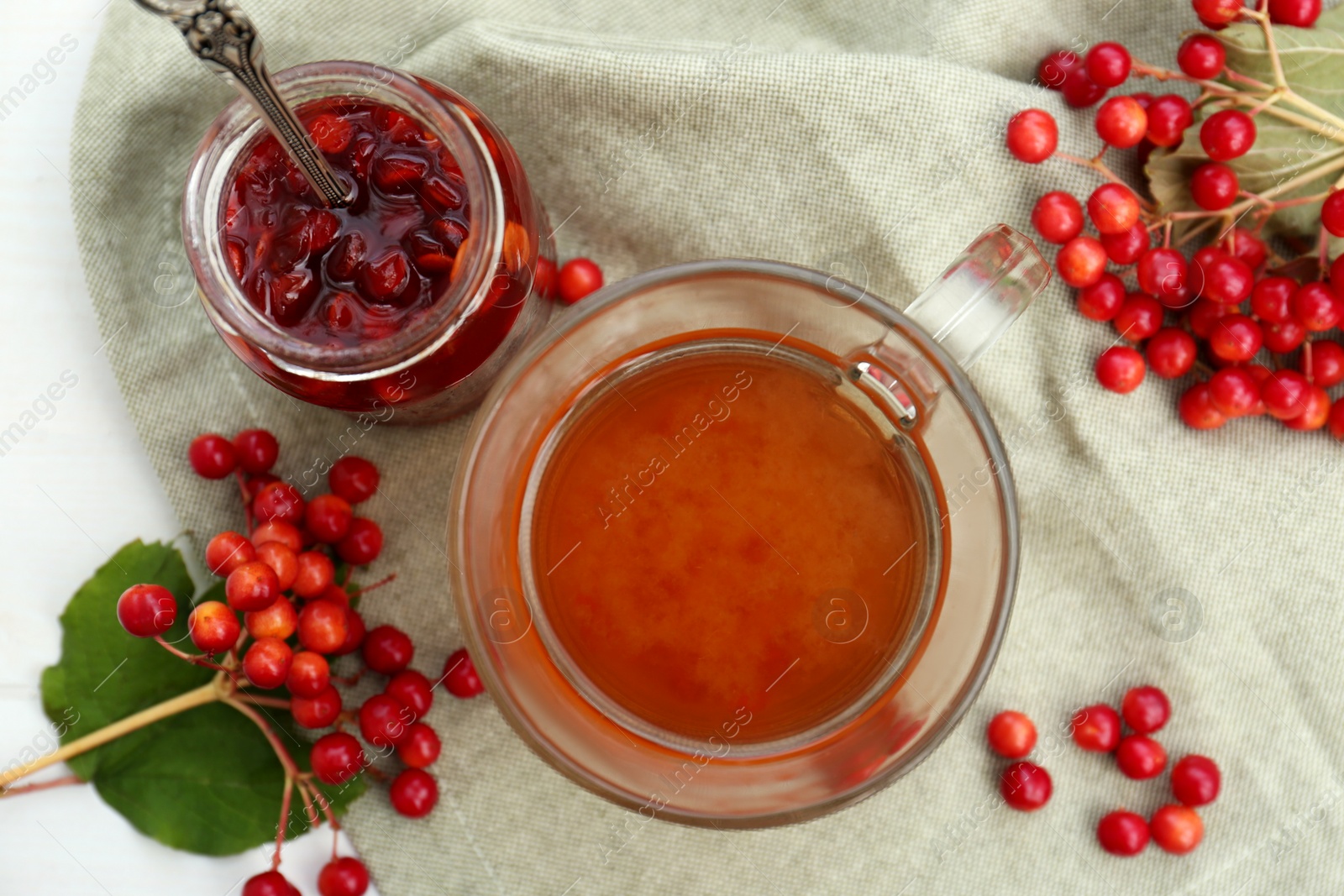 Photo of Cup of tea, jam and ripe viburnum berries on white table, flat lay