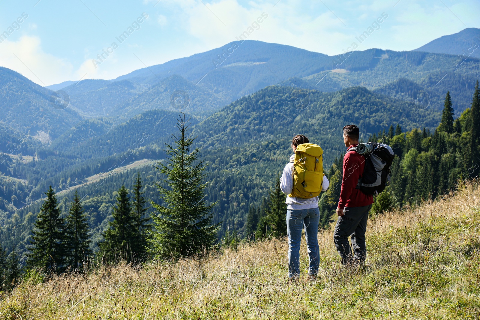 Photo of Couple with backpacks enjoying mountain landscape on sunny day