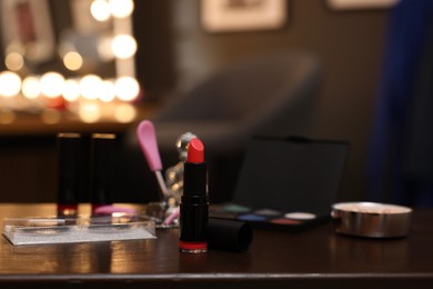 Photo of Red lipstick and other beauty products on wooden table. Makeup room