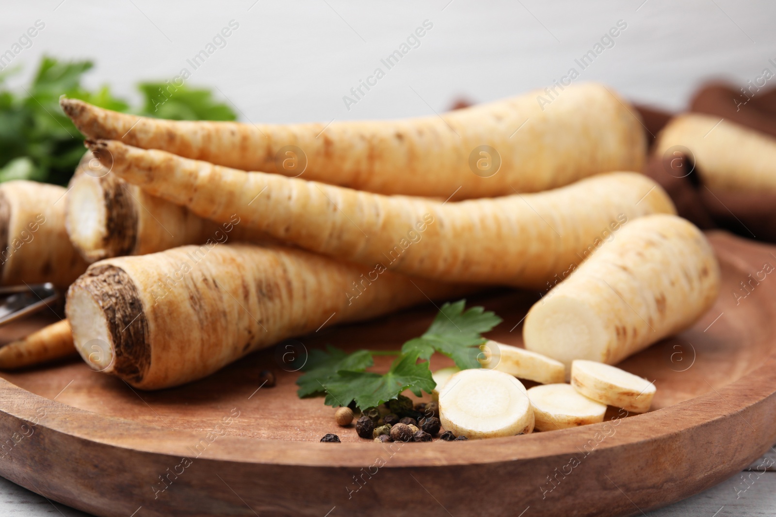 Photo of Raw parsley roots and fresh herb on wooden board, closeup