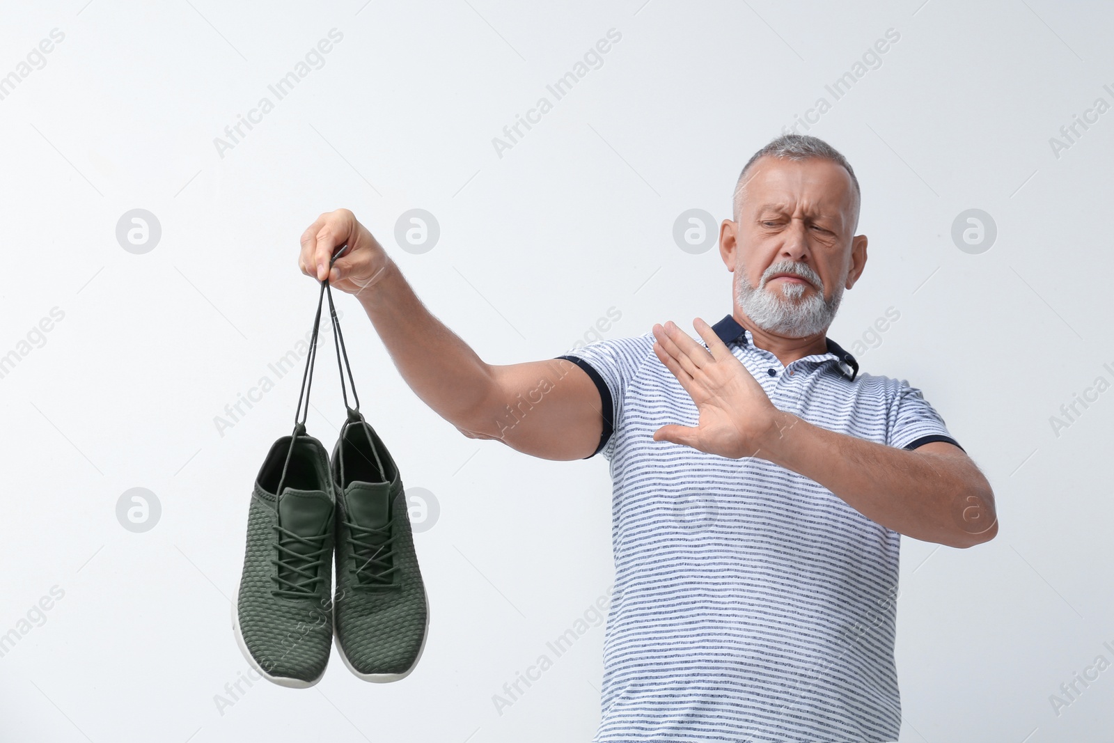 Photo of Man feeling bad smell from shoes on white background. Air freshener