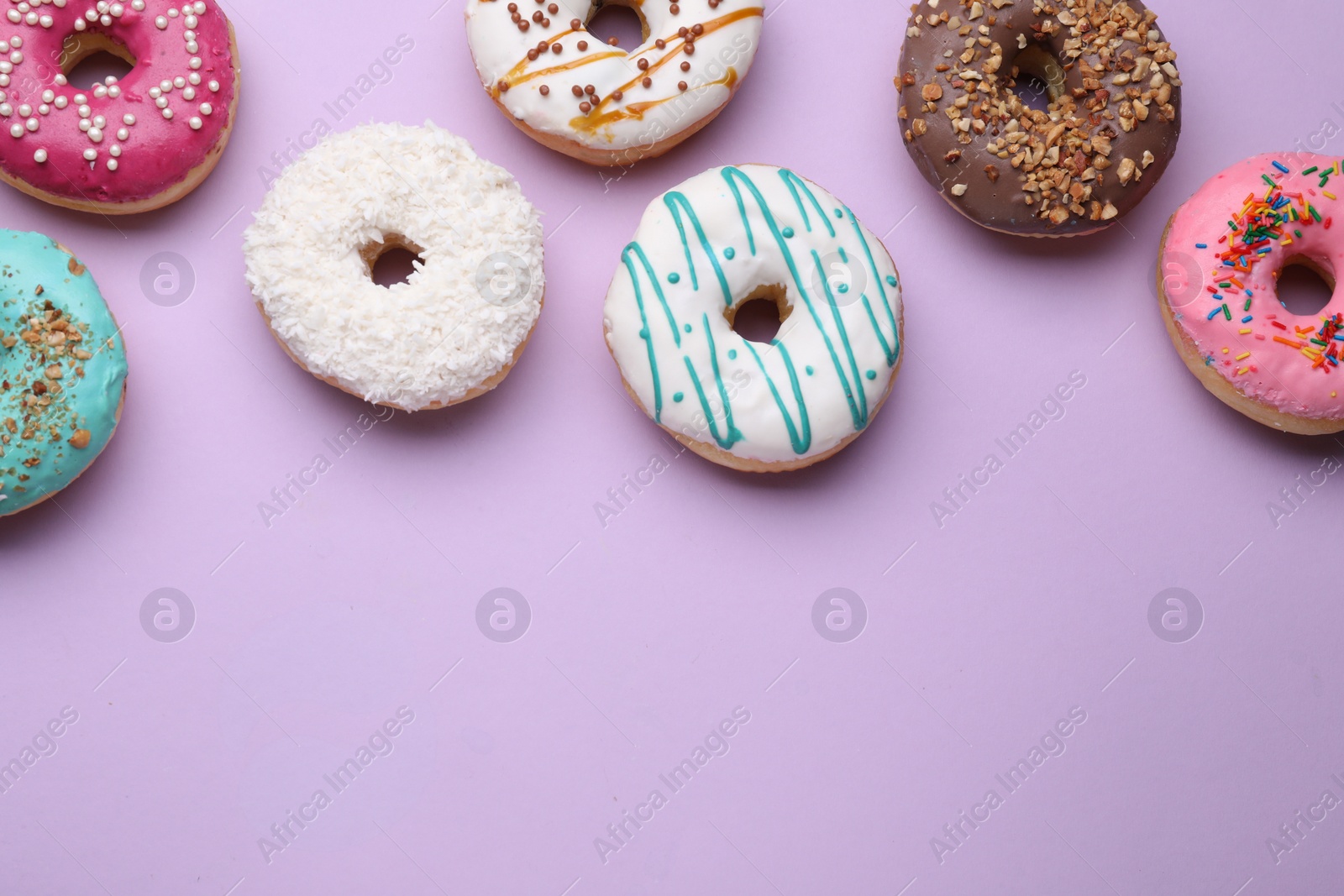 Photo of Different tasty glazed donuts on purple background, flat lay. Space for text