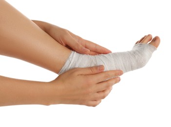 Photo of Woman wrapping foot in medical bandage on white background, closeup