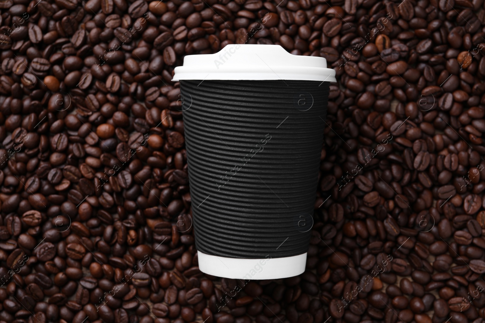 Photo of Coffee to go. Paper cup on roasted beans, top view