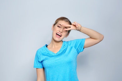 Photo of Happy young woman showing victory gesture on color background