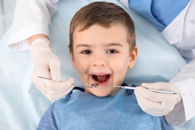 Dentist examining cute boy's teeth in modern clinic