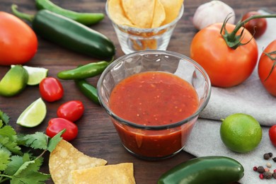 Tasty salsa sauce and different ingredients on wooden table, closeup