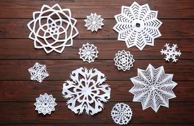 Photo of Flat lay composition with paper snowflakes on wooden background. Winter season