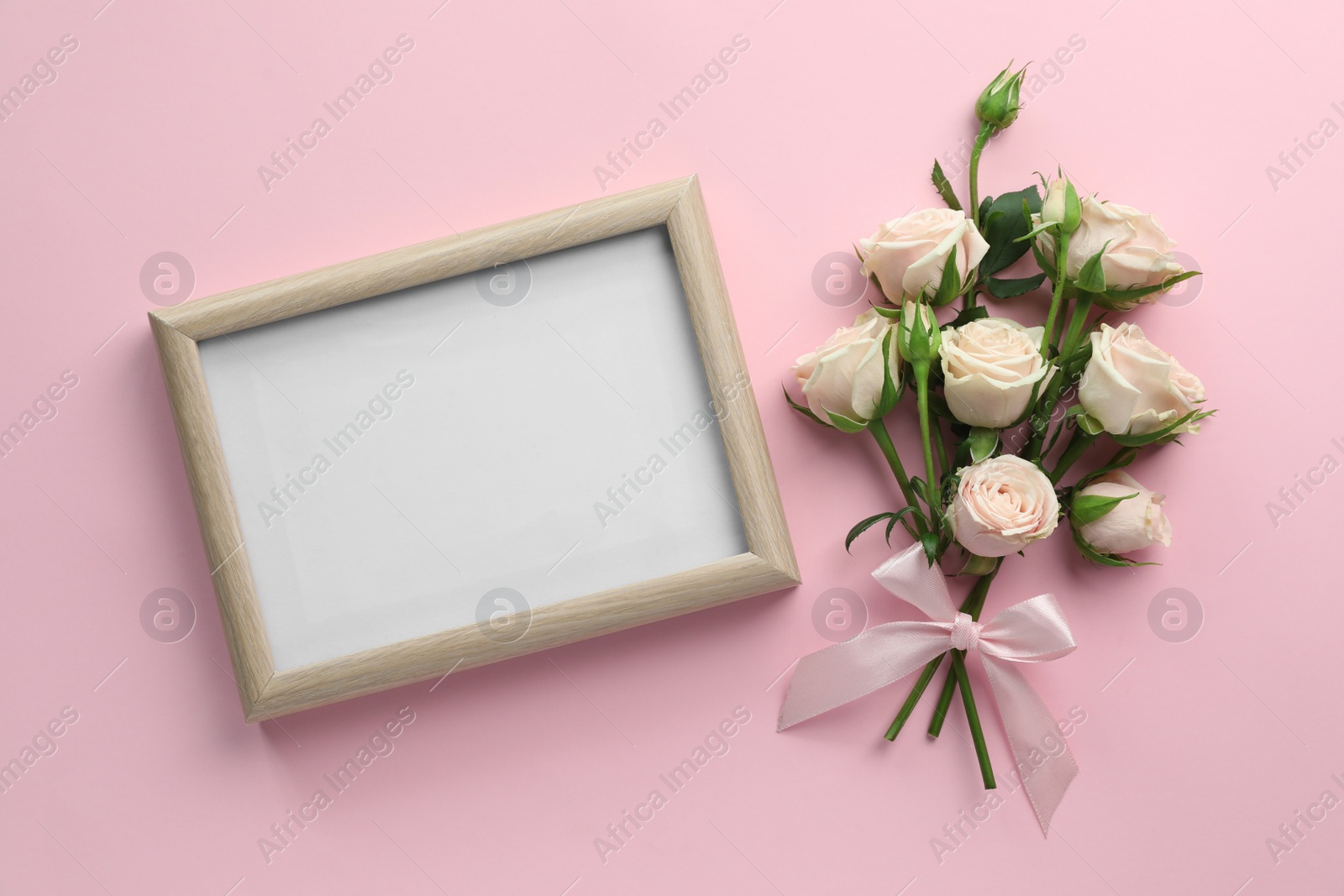 Photo of Beautiful bouquet of roses with blank white board on light pink background, flat lay. Space for text