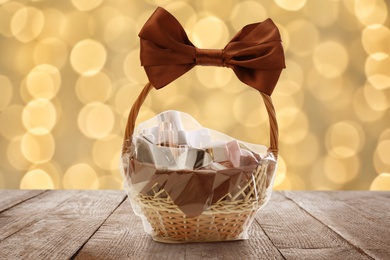 Image of Wicker basket full of cosmetic products on table against blurred festive lights 