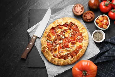 Flat lay composition of tasty galette with tomato and cheese (Caprese galette) on dark textured table