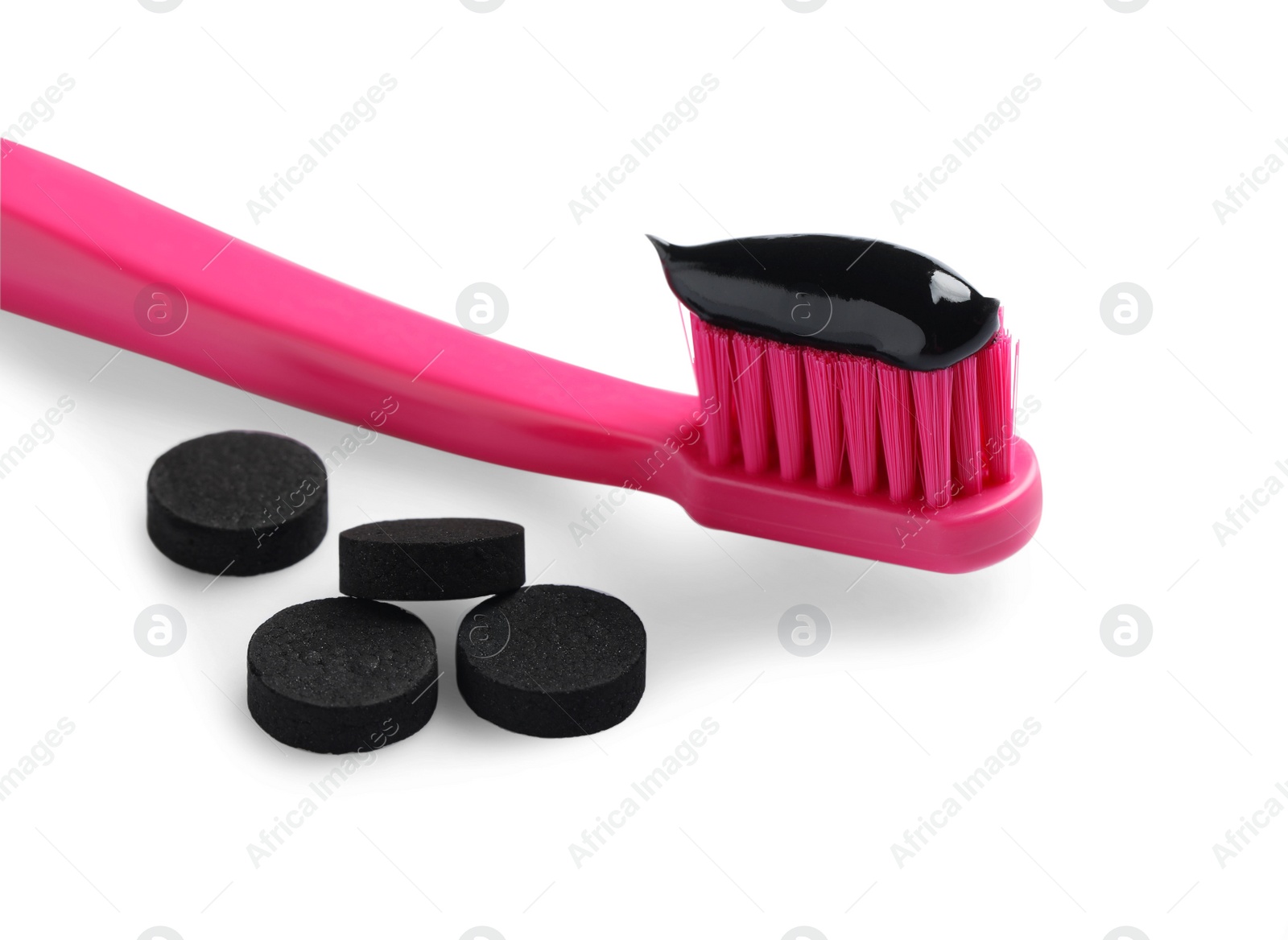 Photo of Brush with charcoal toothpaste and black pills on white background