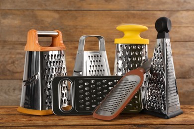 Photo of Different stainless steel graters on wooden table