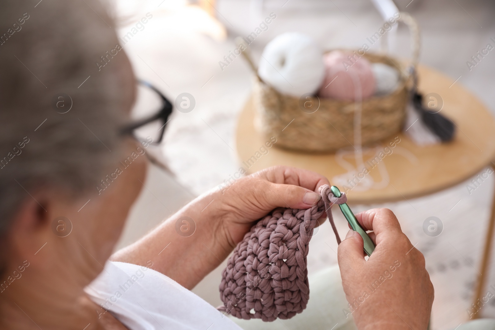 Photo of Elderly woman crocheting at home, closeup. Creative hobby