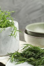 Photo of Plate and mortar with fresh tarragon leaves on table, closeup