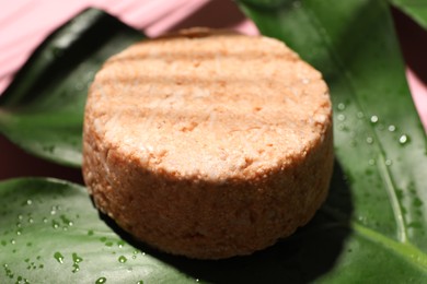 Photo of Solid shampoo bar and leaf on pink background, closeup. Hair care