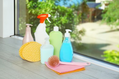 Photo of Different cleaning supplies and tools on window sill indoors