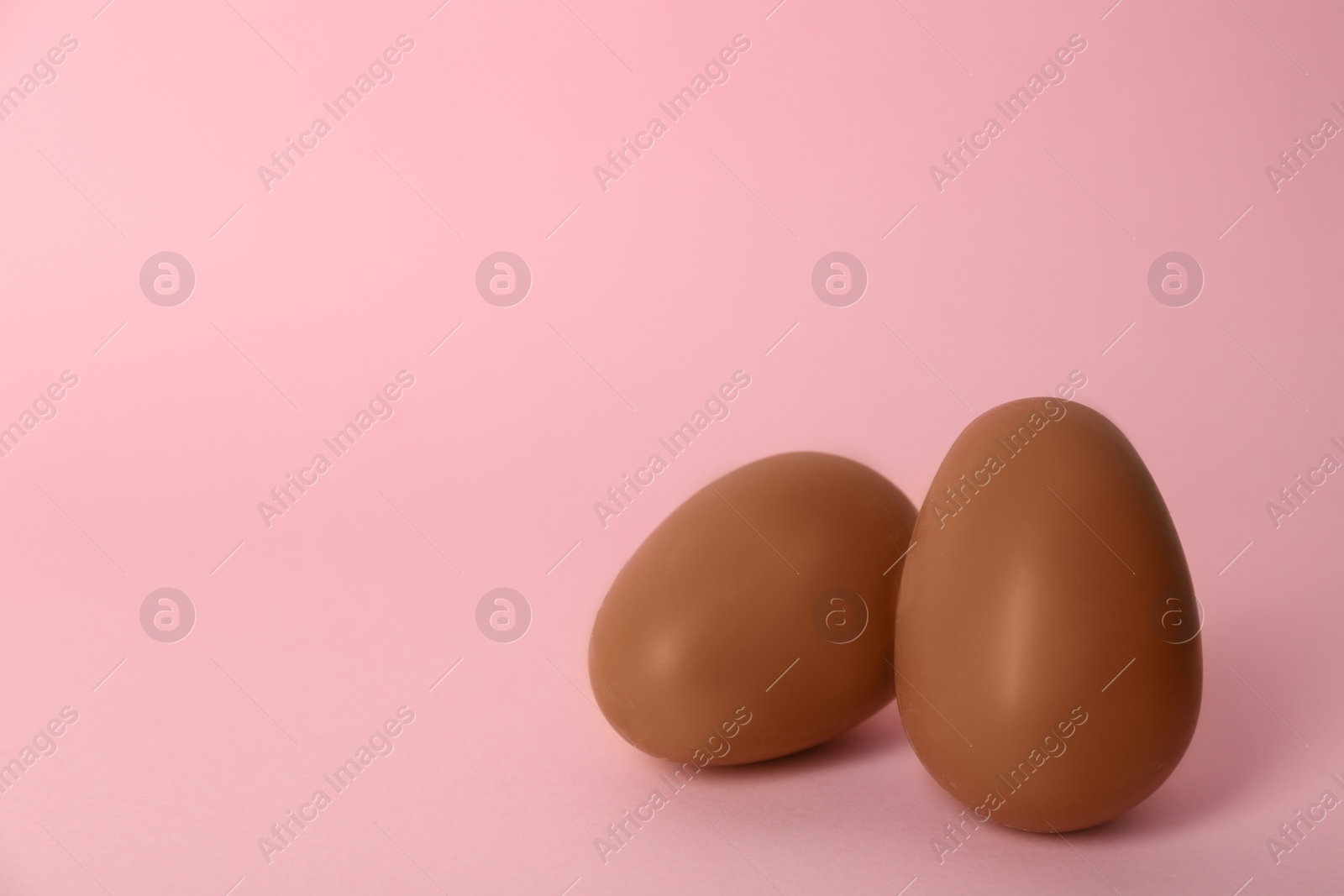 Photo of Sweet chocolate eggs on pink background. Space for text