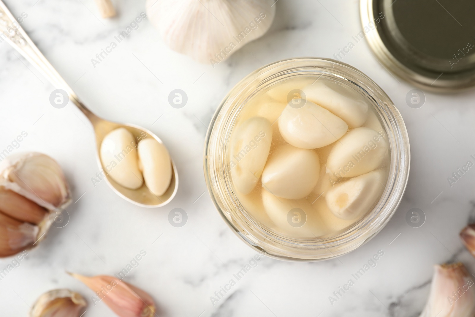 Photo of Preserved garlic in glass jar on table, top view. Space for text