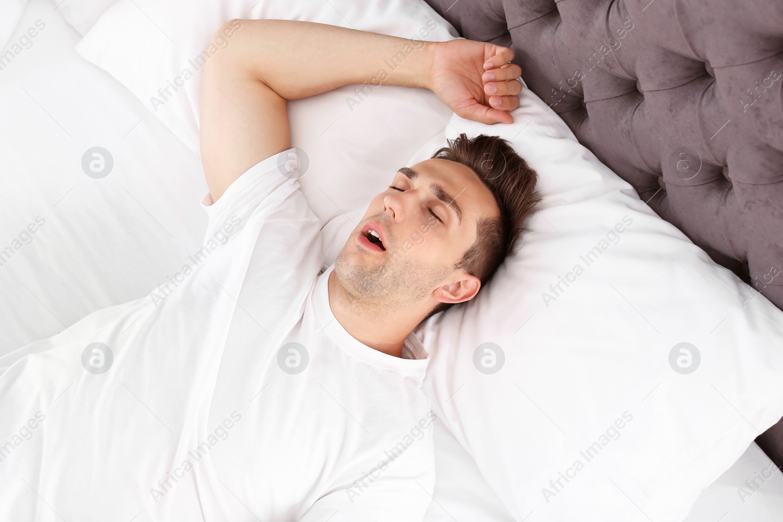 Photo of Young man sleeping in bed at home, top view