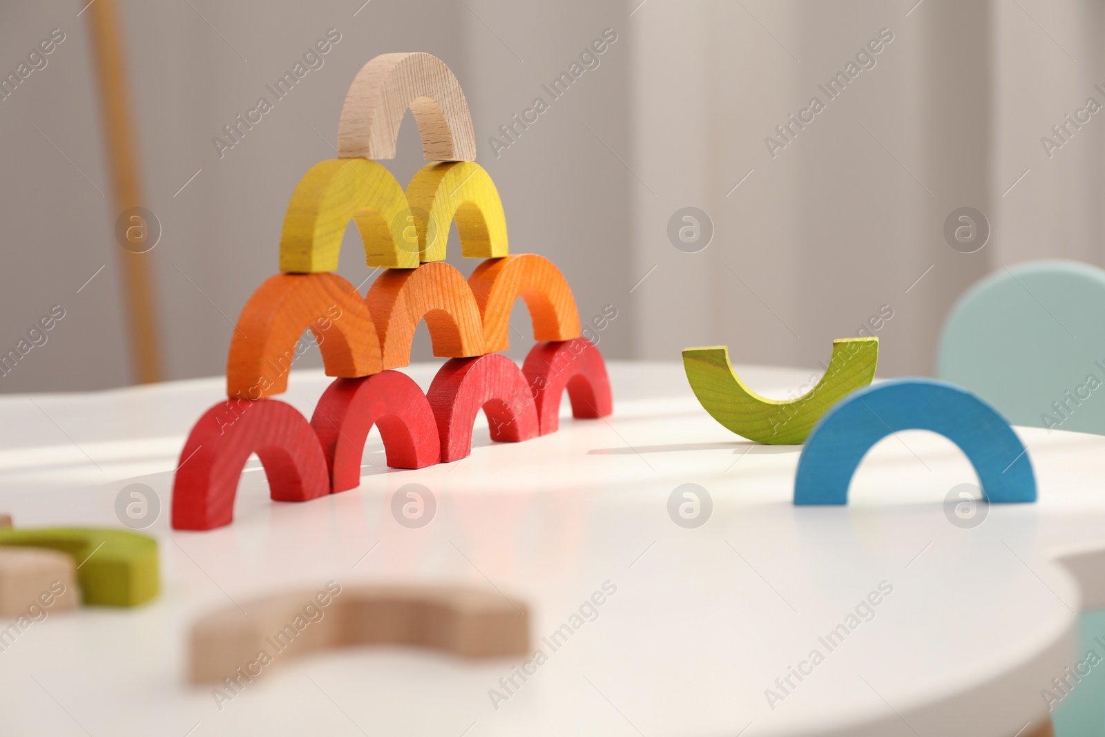 Photo of Colorful wooden pieces of play set on white table indoors. Educational toy for motor skills development