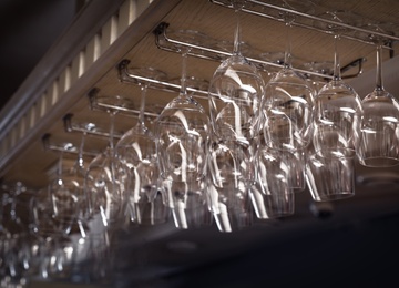 Photo of Set of empty clean glasses on bar racks