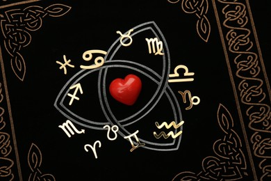 Zodiac signs and red heart on book, flat lay