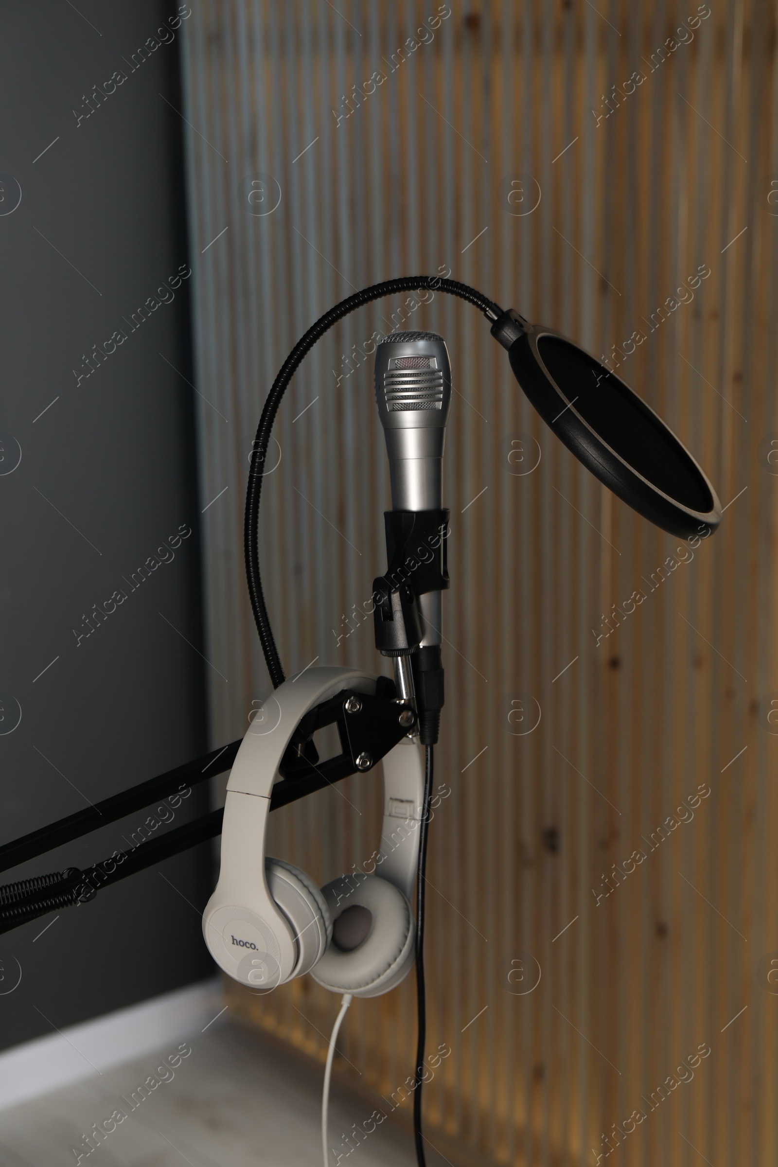 Photo of Stand with microphone, headphones and pop filter indoors. Sound recording and reinforcement