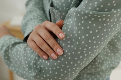 Woman touching shirt made of smooth fabric indoors, closeup