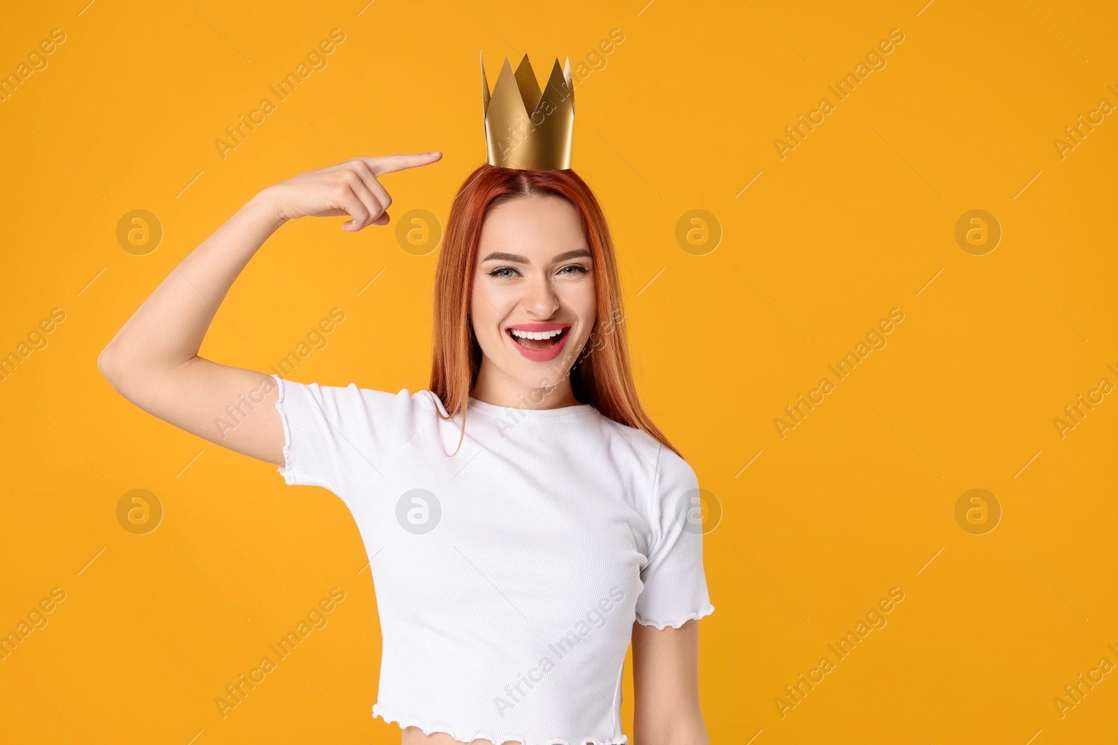 Photo of Beautiful young woman with princess crown on orange background