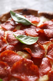 Tasty pepperoni pizza with basil on table, closeup