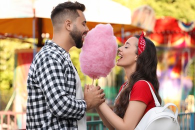 Happy couple eating cotton candy at funfair