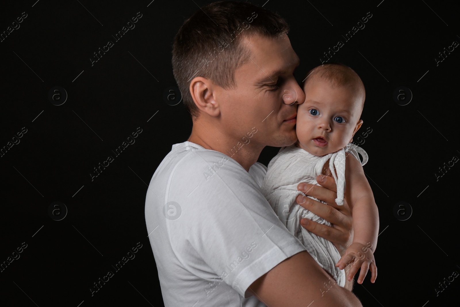 Photo of Happy father with his little baby on black background