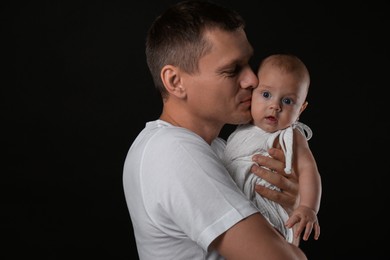 Photo of Happy father with his little baby on black background