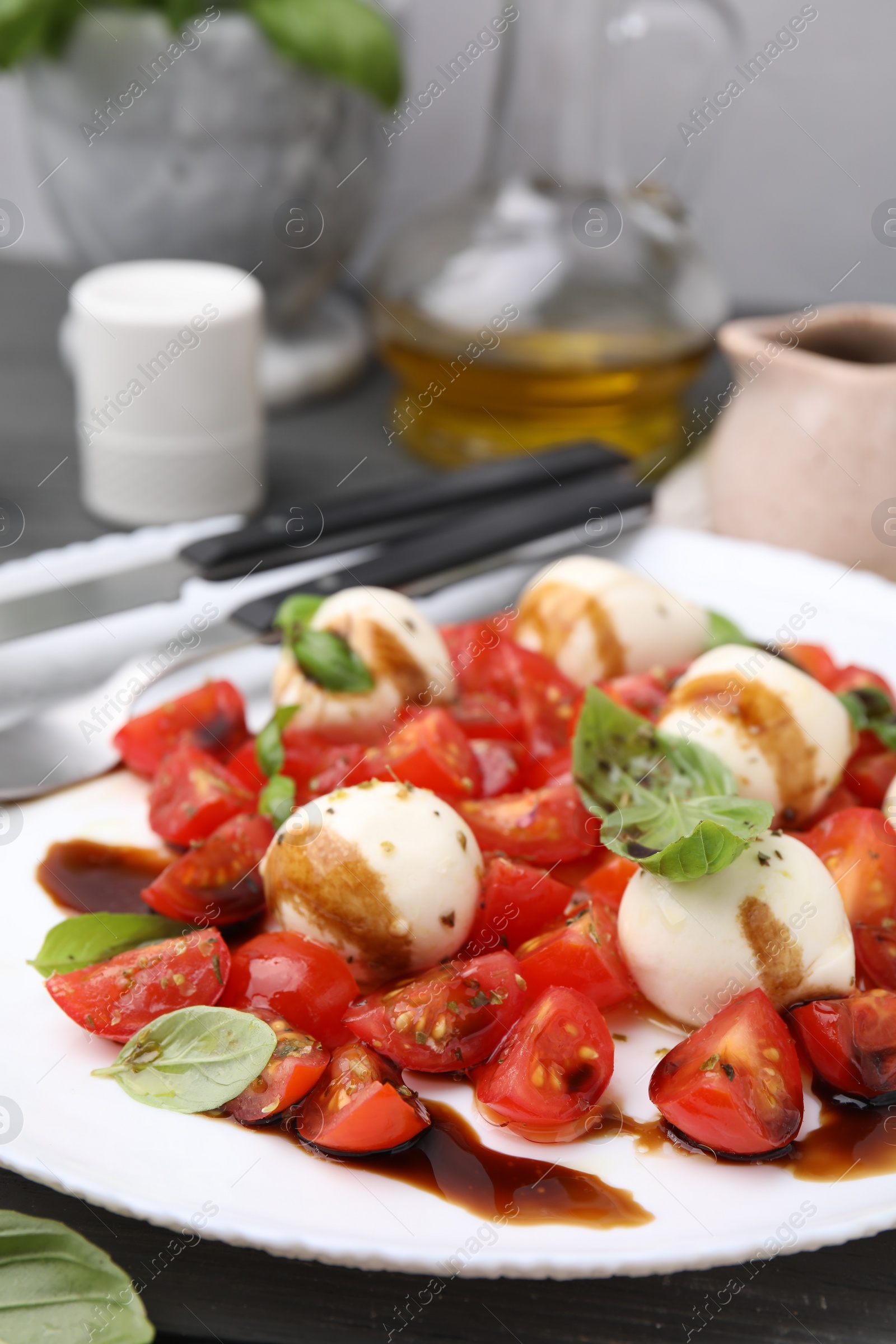 Photo of Tasty salad Caprese with tomatoes, mozzarella balls, basil and balsamic vinegar on table, closeup. Space for text