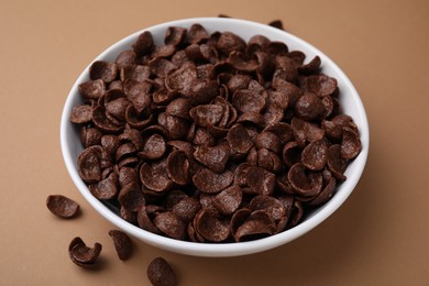 Photo of Breakfast cereal. Chocolate corn flakes in bowl on brown table, closeup