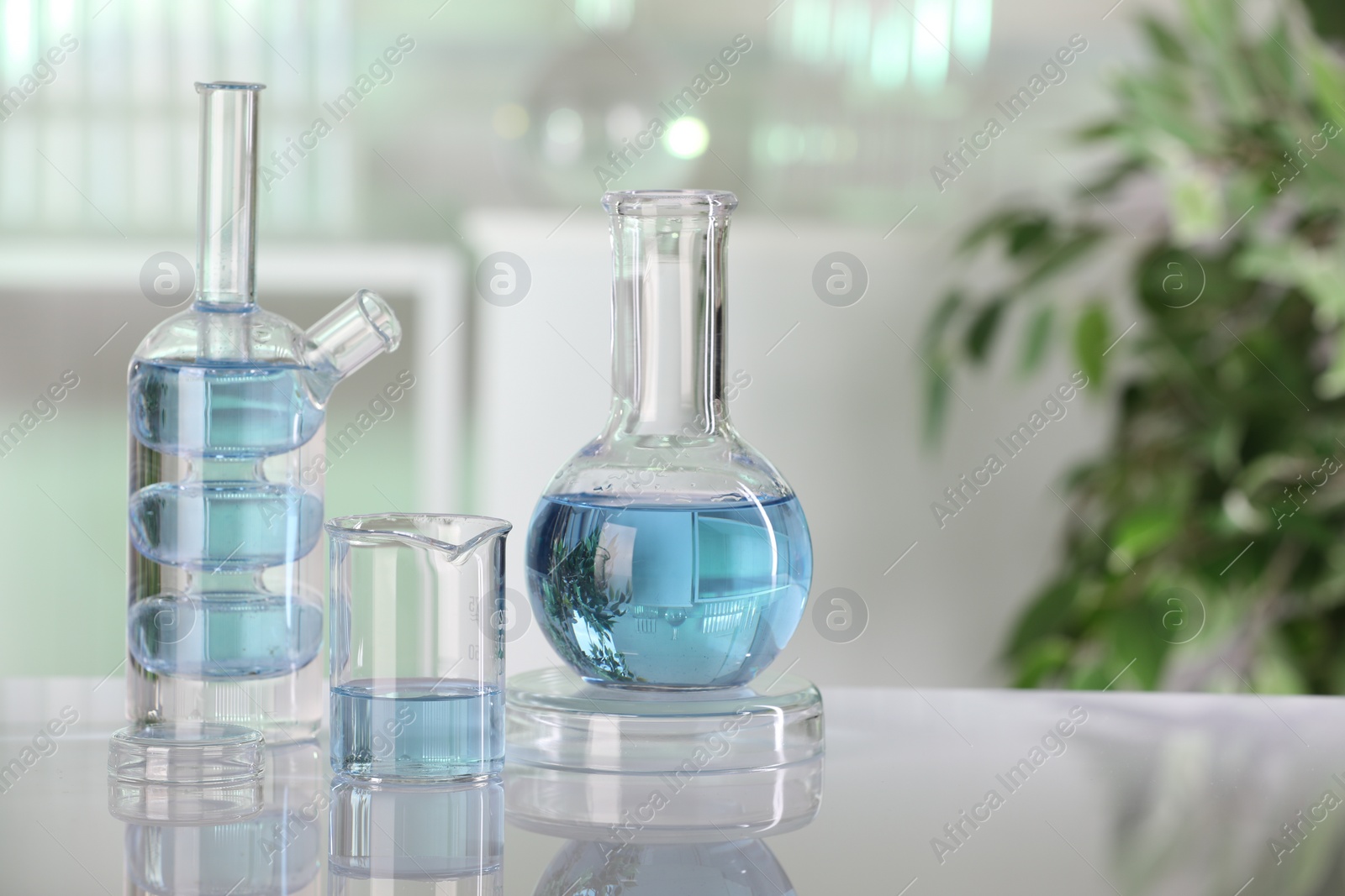 Photo of Laboratory analysis. Different glassware with liquid on white table indoors. Space for text