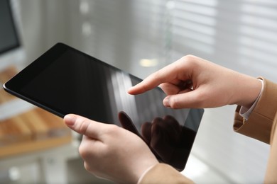 Photo of Businesswoman using modern tablet in office, closeup