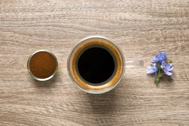 Photo of Glass cup of delicious chicory drink, powder and flowers on wooden table, flat lay