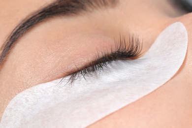 Photo of Young woman undergoing eyelashes extensions procedure, closeup