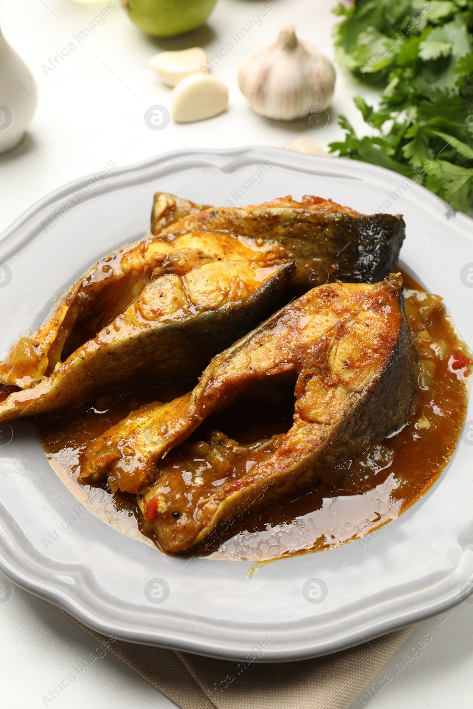 Photo of Tasty fish curry on white table, closeup. Indian cuisine