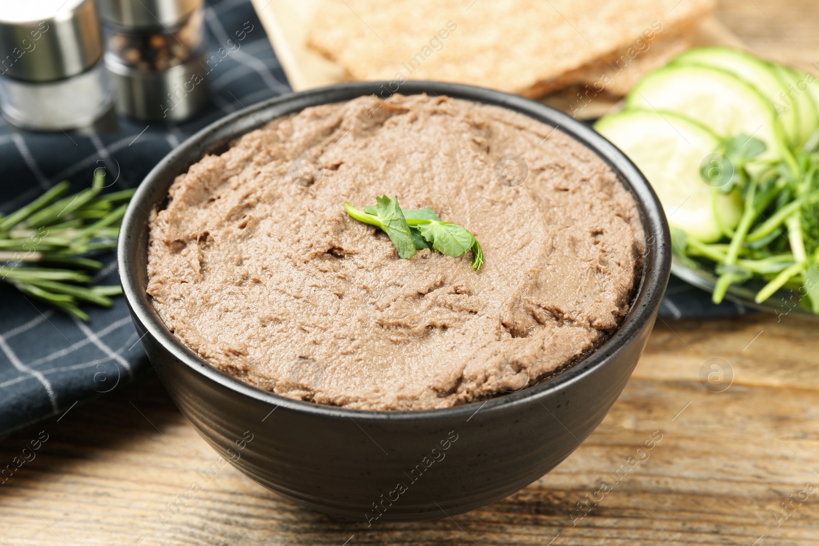 Photo of Tasty liver pate with herb in bowl on wooden table, closeup