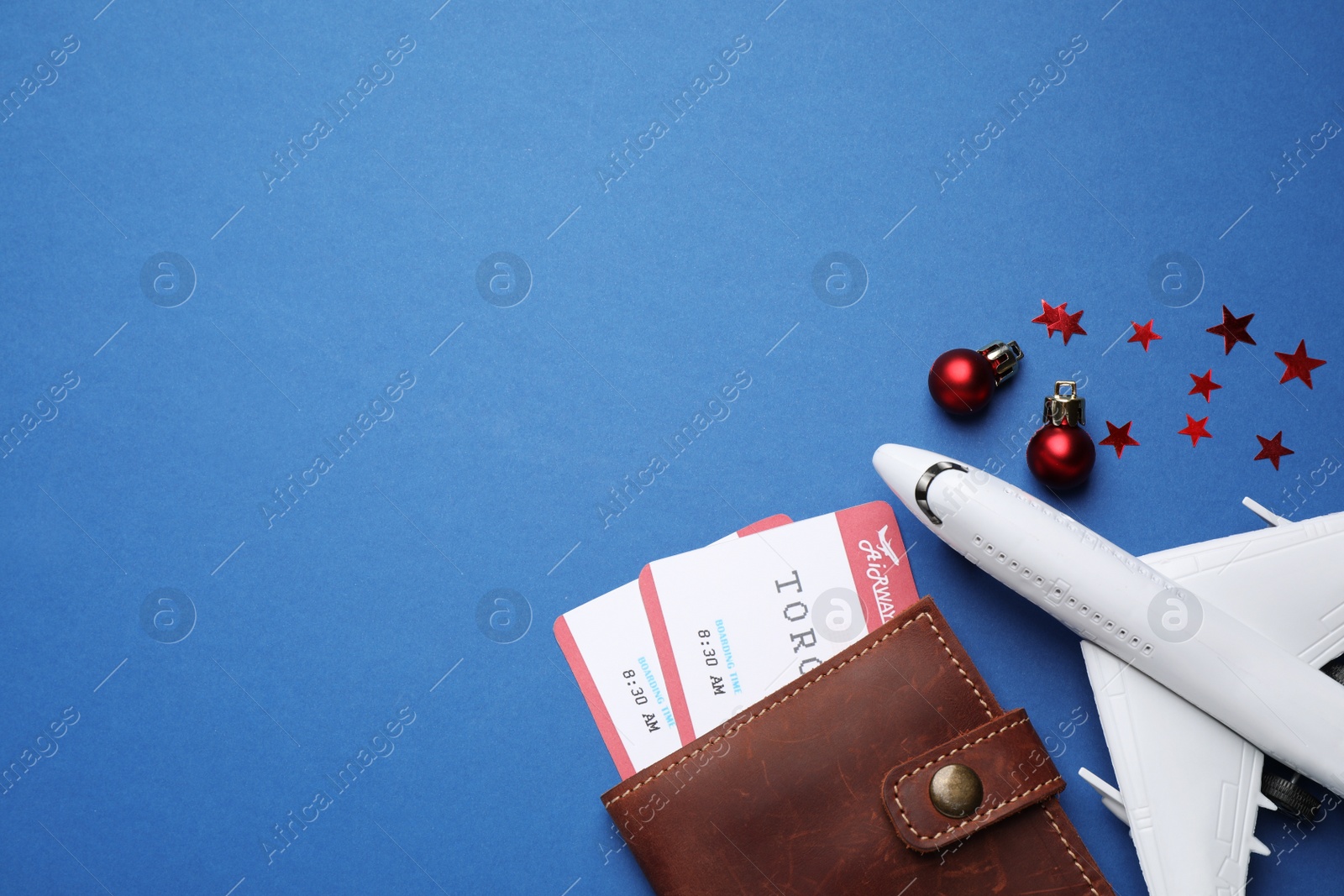 Photo of Toy airplane, festive decor, airline tickets and space for text on blue background, flat lay. Christmas vacation