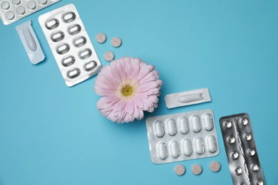 Photo of Many gynecological pills and gerbera flower on light blue background, flat lay
