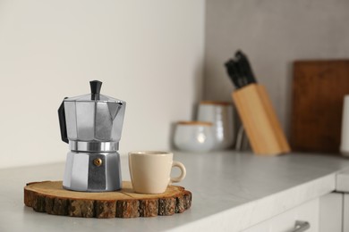 Photo of Ceramic cup and moka pot on light countertop in kitchen, space for text