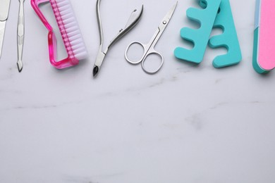 Photo of Set of pedicure tools on white marble table, flat lay. Space for text