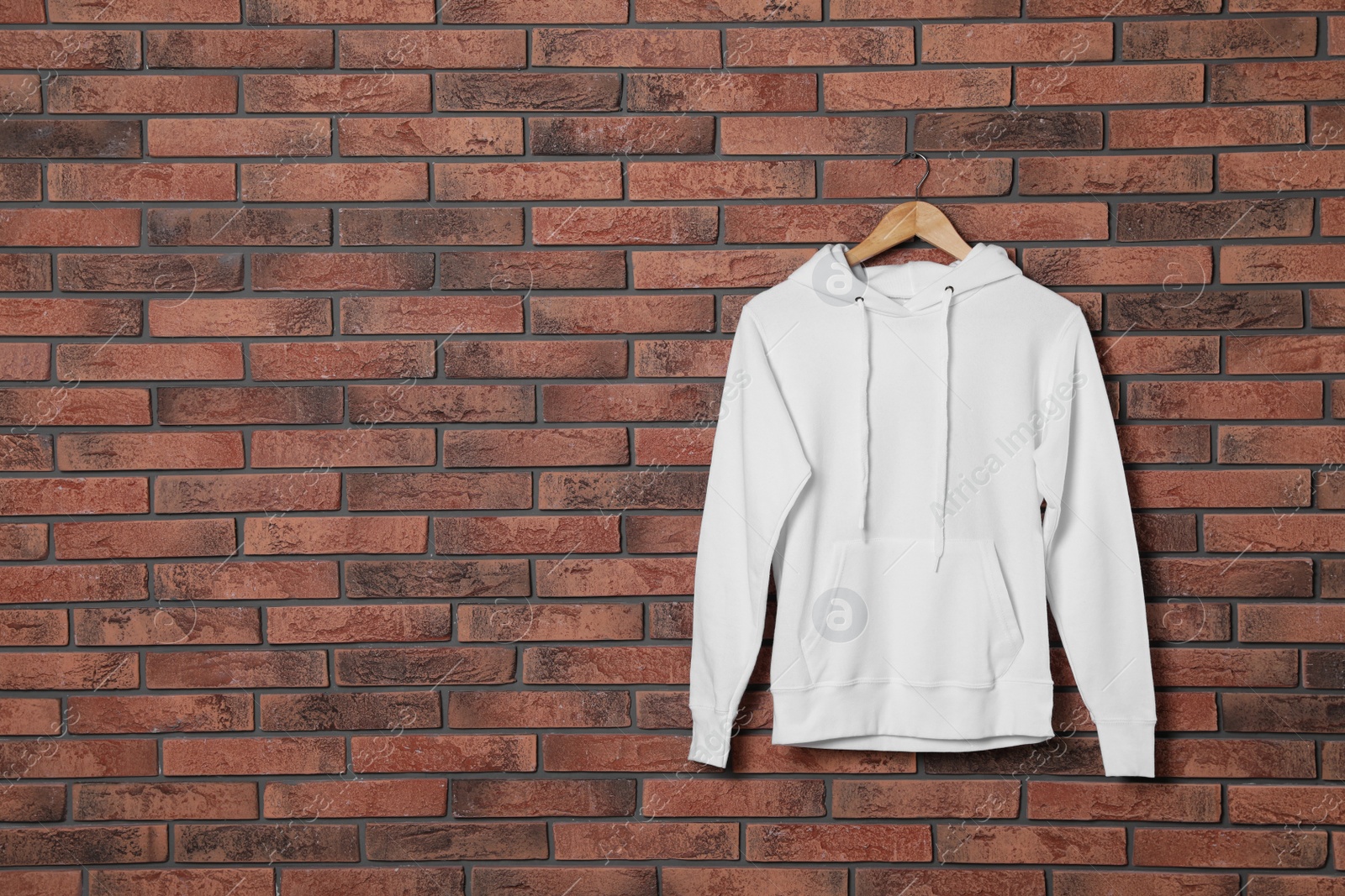 Photo of Hanger with new sweater on brick wall, mock up for design