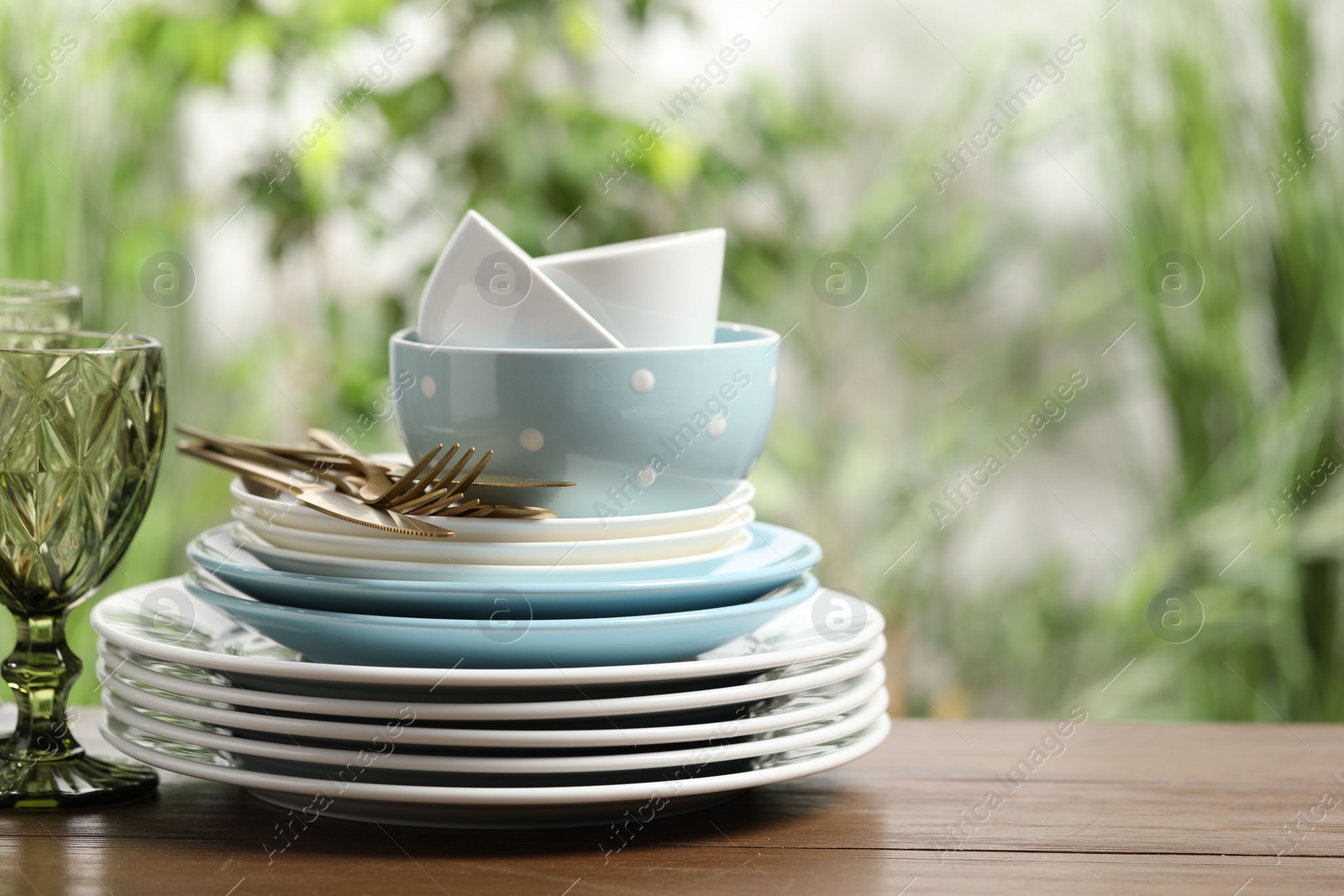 Photo of Beautiful ceramic dishware, glass and cutlery on wooden table outdoors, space for text