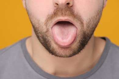 Photo of Man showing his tongue on yellow background, closeup